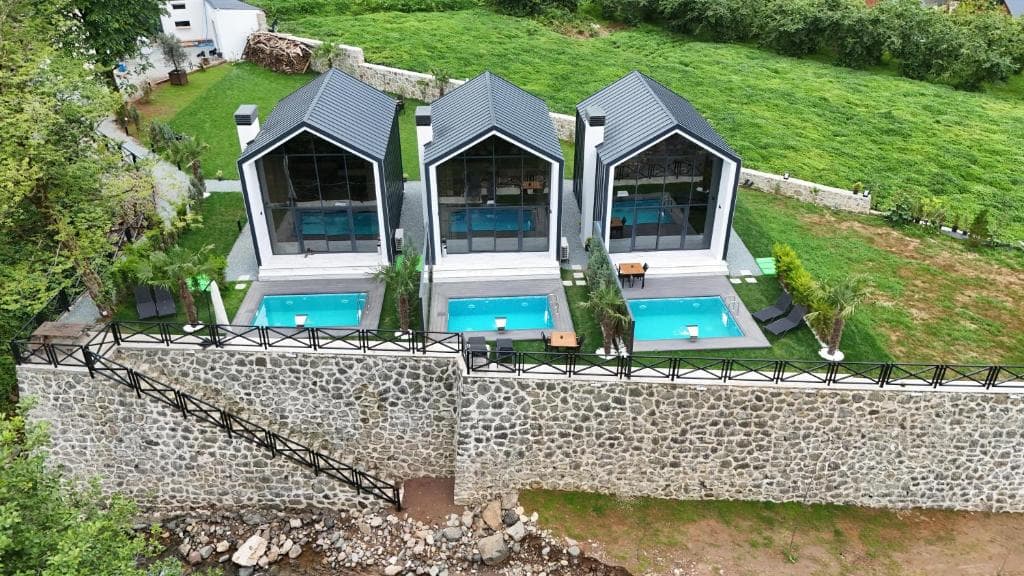 Dere kenarındaki üç Rize Roof Villa bungalovunun drone görünümü