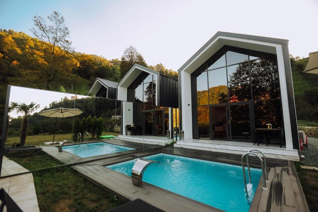 Rize Roof Villa Bungalov — gün batımında dere kenarındaki villaların dış görünümü